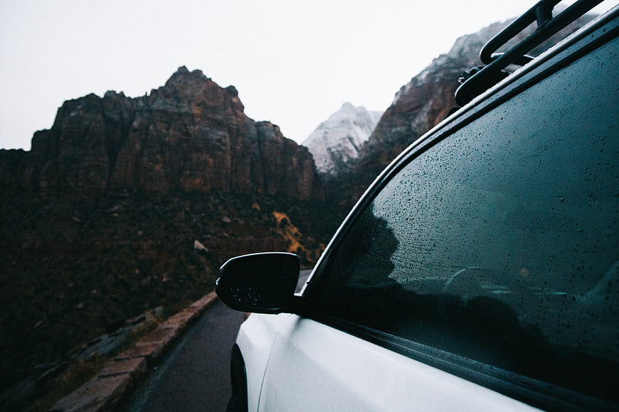 White SUV on Mountain Road with Raindrops