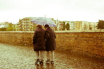 Senior Couple Walking Under Umbrella In Rain