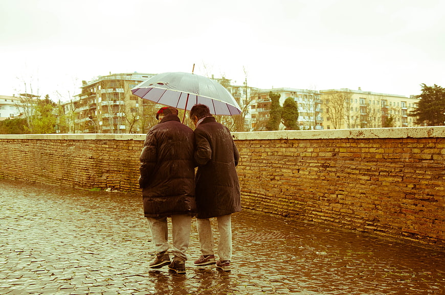 Senior Couple Walking Under Umbrella In Rain