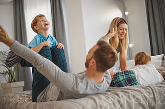 Happy family playing together on bed in pajamas