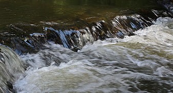 Flowing River Water Over Rocks with White Foam
