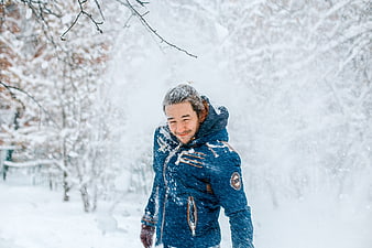 Happy man in blue jacket walking in heavy snowfall
