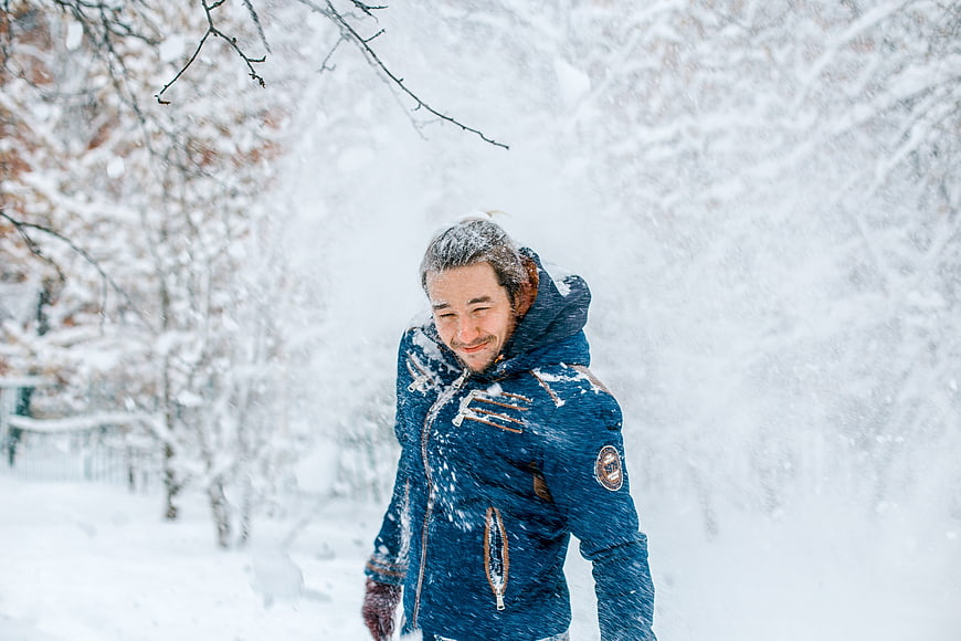 Happy man in blue jacket walking in heavy snowfall
