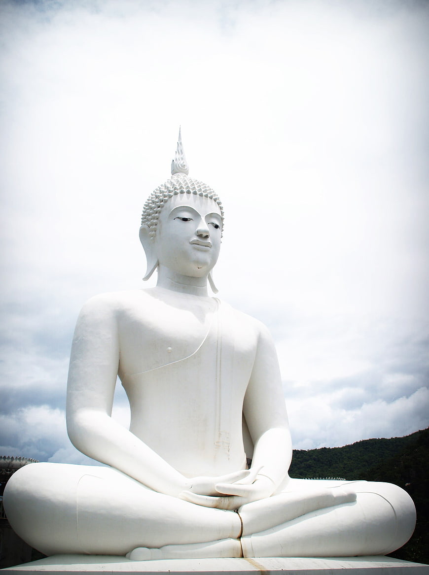 White Buddha Statue Meditating in Lotus Position Against Cloudy Sky
