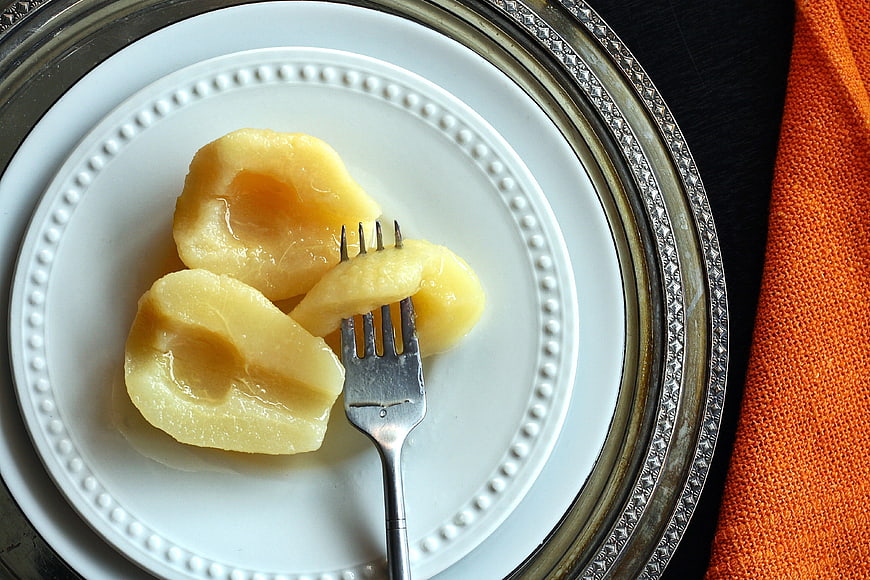 Canned Pears on White Plate with Fork and Silver Charger