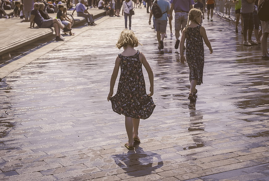 Two young girls walking away on wet pavement