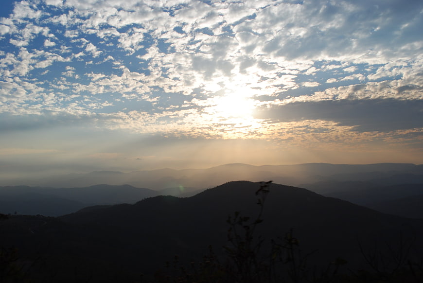 Sunset over layered mountain ranges with dramatic clouds