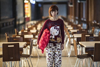 Woman in pajamas holding pillow in empty dining hall