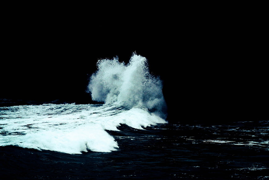 Dramatic crashing ocean wave against dark background