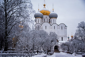 Snow-covered Orthodox church with golden domes in winter
