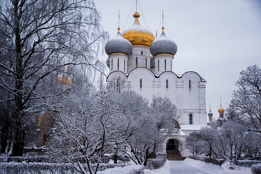 Snow-covered Orthodox church with golden domes in winter