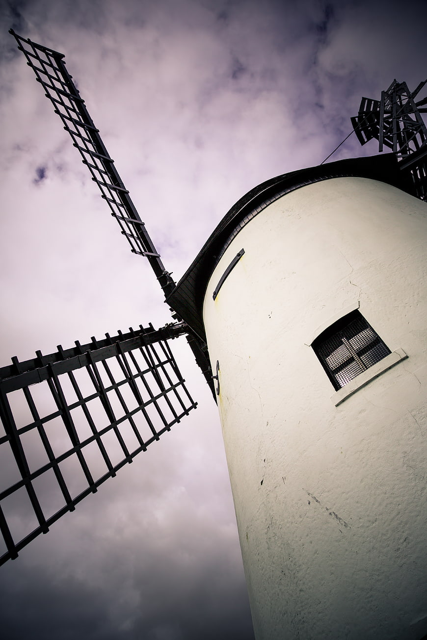Low angle view of white windmill against dramatic purple sky