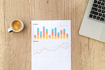 Business Analytics Report with Laptop and Coffee on Wooden Desk