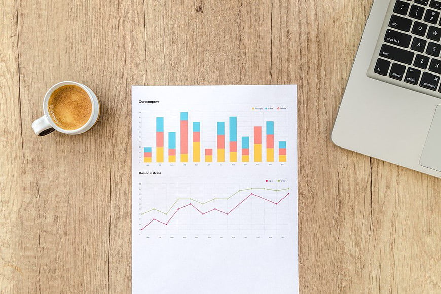 Business Analytics Report with Laptop and Coffee on Wooden Desk
