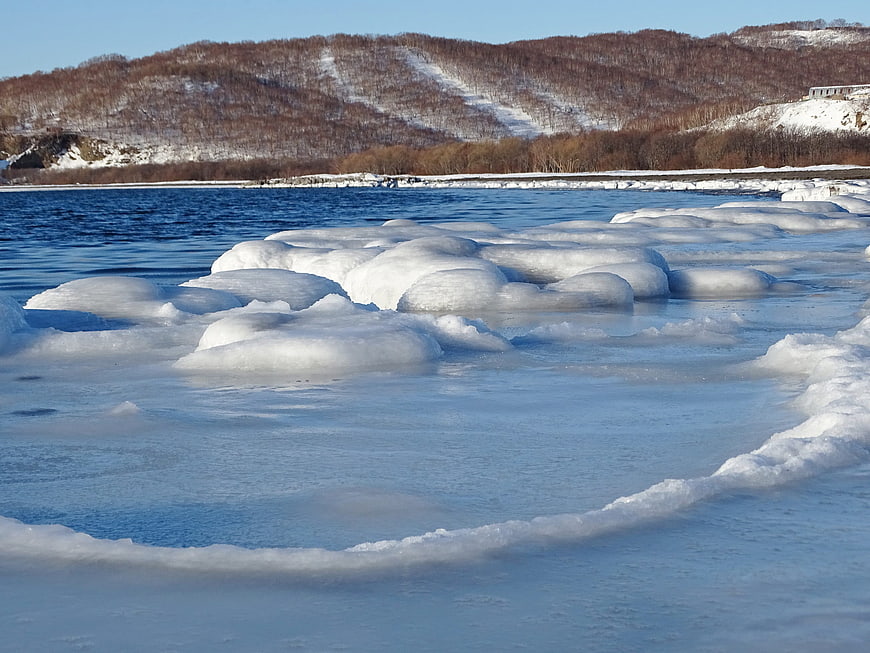 Frozen ice chunks on a winter river with snowy hills