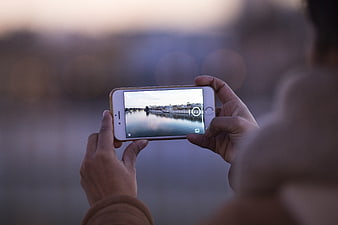 Hands holding smartphone taking photo of cityscape at dusk