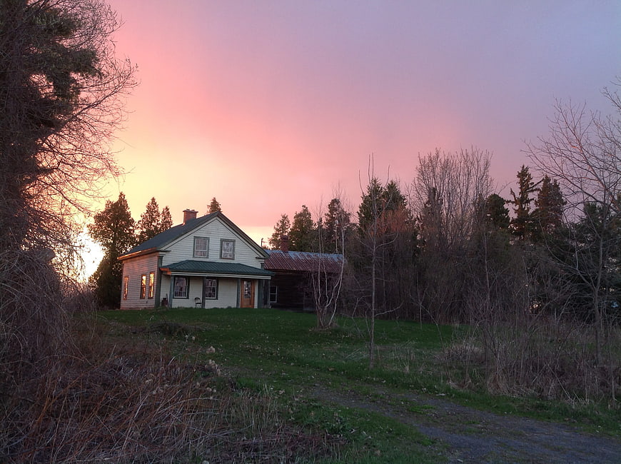 Rustic house with pink sunset sky and bare trees
