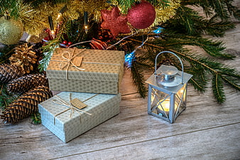 Christmas gifts under tree with lantern and pinecones