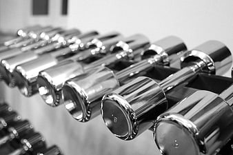 Black and white close-up of chrome dumbbells on a rack
