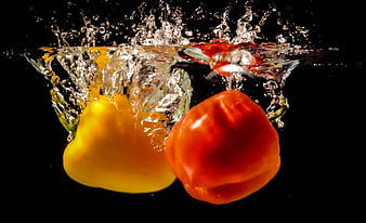 Red and yellow bell peppers splashing into water