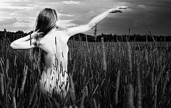 Black and white portrait of a nude woman in a field