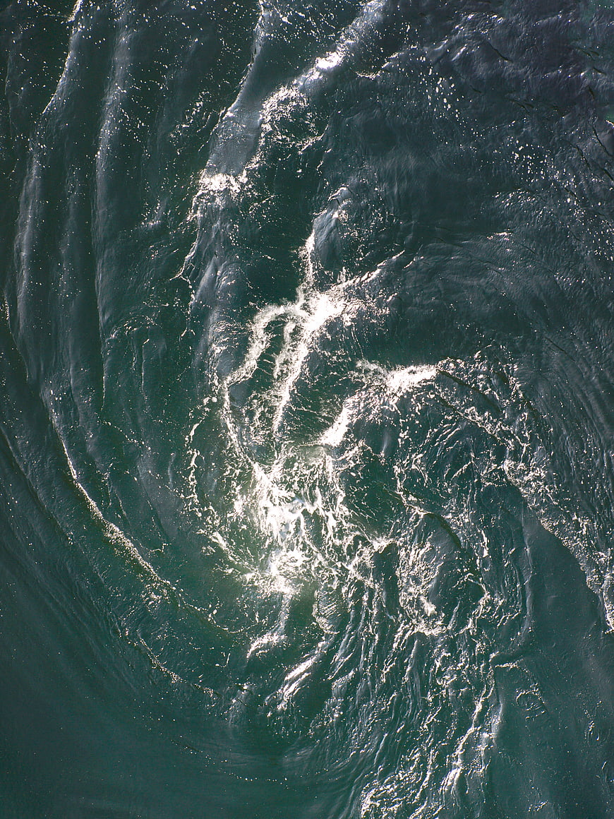 Aerial View of Swirling Ocean Water with Sunlight Reflections