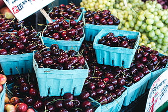 Fresh dark red cherries in blue baskets at a farmers market