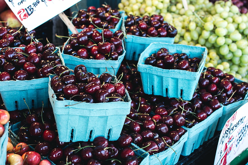 Fresh dark red cherries in blue baskets at a farmers market