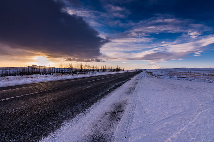 Snowy Winter Road at Dusk with Dramatic Clouds
