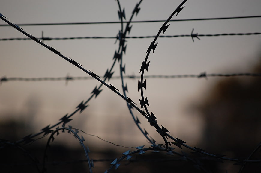 Close-up of barbed wire fence against blurred background