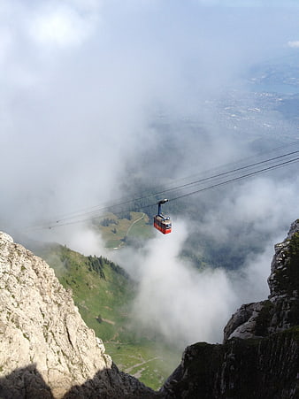 Red Cable Car Suspended Over Misty Mountain Valley