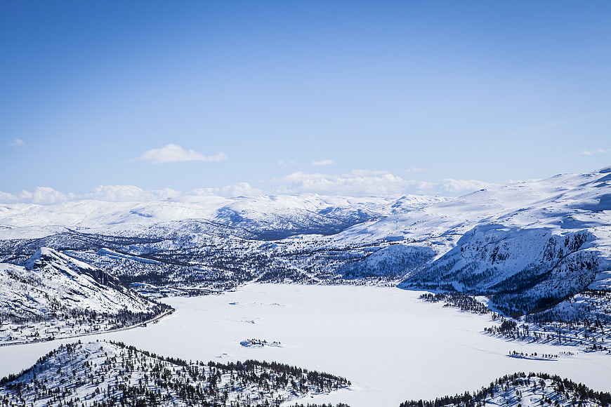 Aerial View of Frozen Lake Surrounded by Snowy Mountains