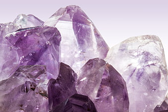 Close-up of raw purple amethyst crystal cluster on white background