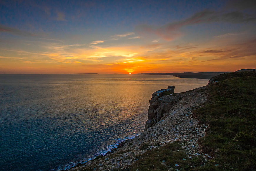 Sunset over ocean from rocky coastal cliff