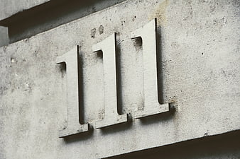 Metal number 111 mounted on textured concrete wall