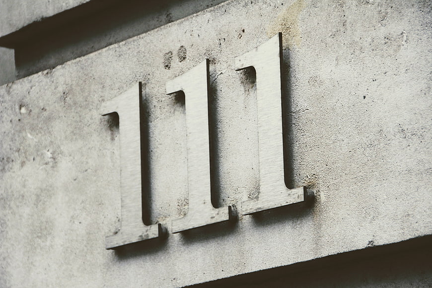 Metal number 111 mounted on textured concrete wall