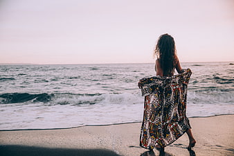 Woman in Patterned Dress Walking on Beach at Sunset