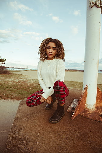 Stylish woman in plaid pants posing by the seaside