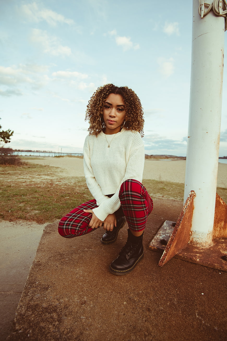 Stylish woman in plaid pants posing by the seaside