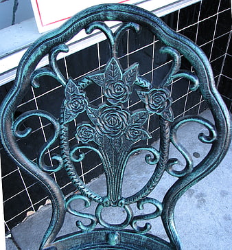 Close-up of ornate green metal chair back with rose design