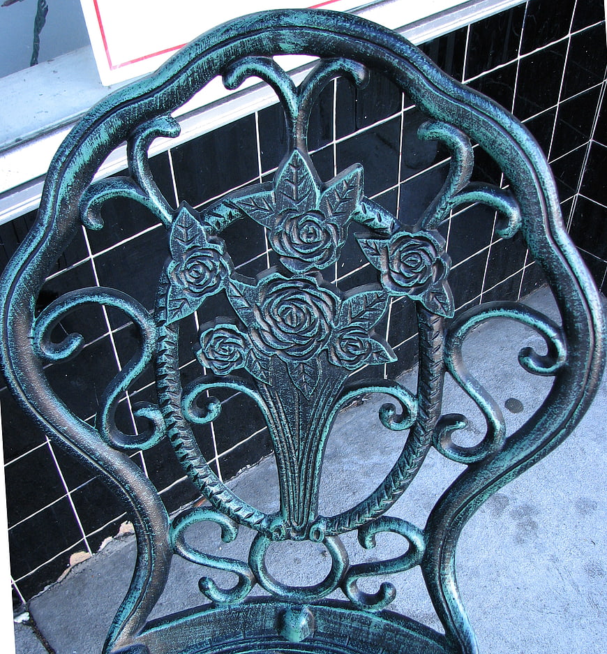 Close-up of ornate green metal chair back with rose design