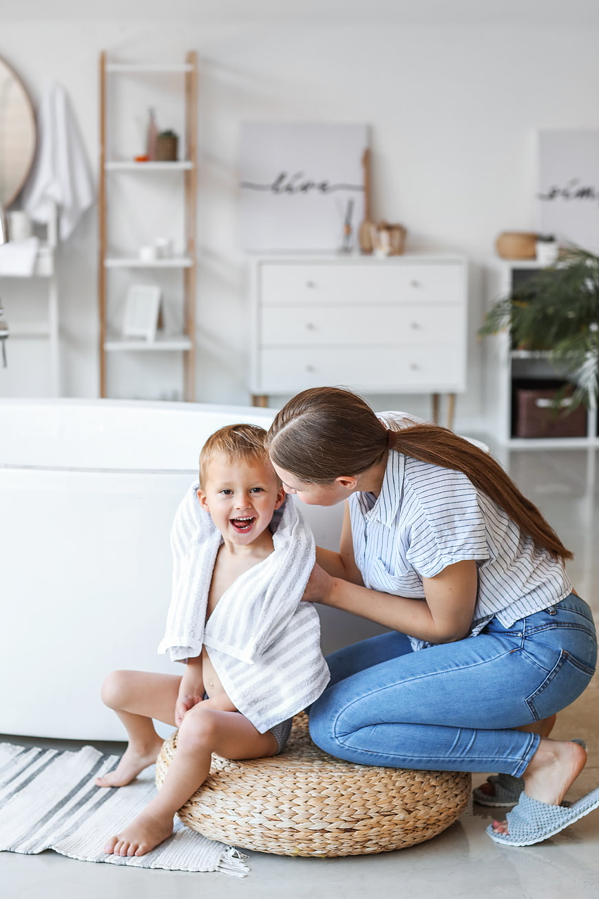 Happy Mother Drying Laughing Boy with Towel in Bathroom