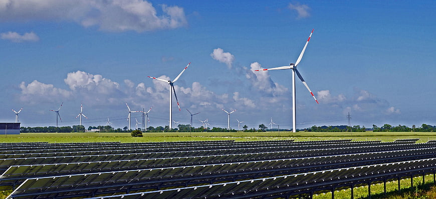 Solar panels and wind turbines in green field