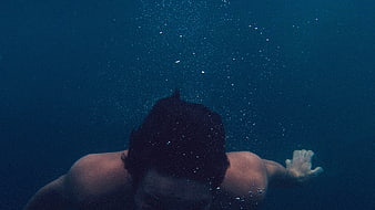 Underwater shot of man swimming with rising bubbles