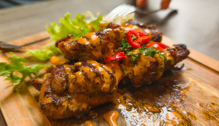Grilled chicken drumsticks with sauce on wooden board