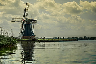 Traditional Dutch Windmill by Lake with Cloudy Sky