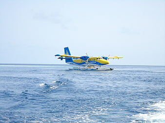 Blue and yellow seaplane floating on calm ocean water