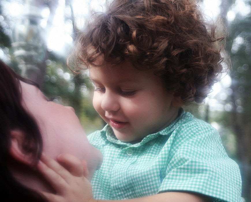 Tender moment between mother and curly-haired toddler outdoors