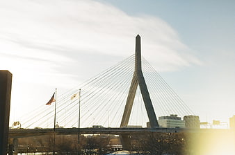 Modern cable-stayed bridge with American flag and sun flare