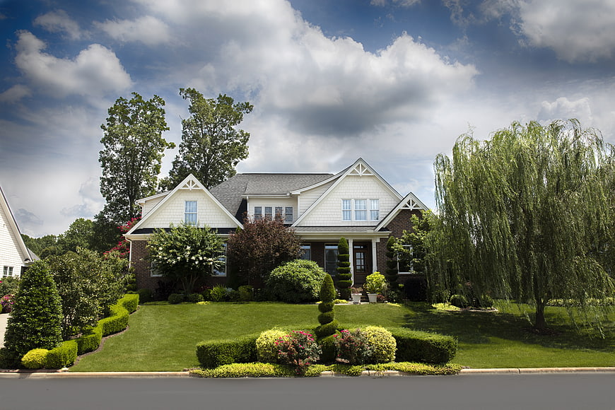Suburban Brick And White House Exterior With Manicured Front Lawn